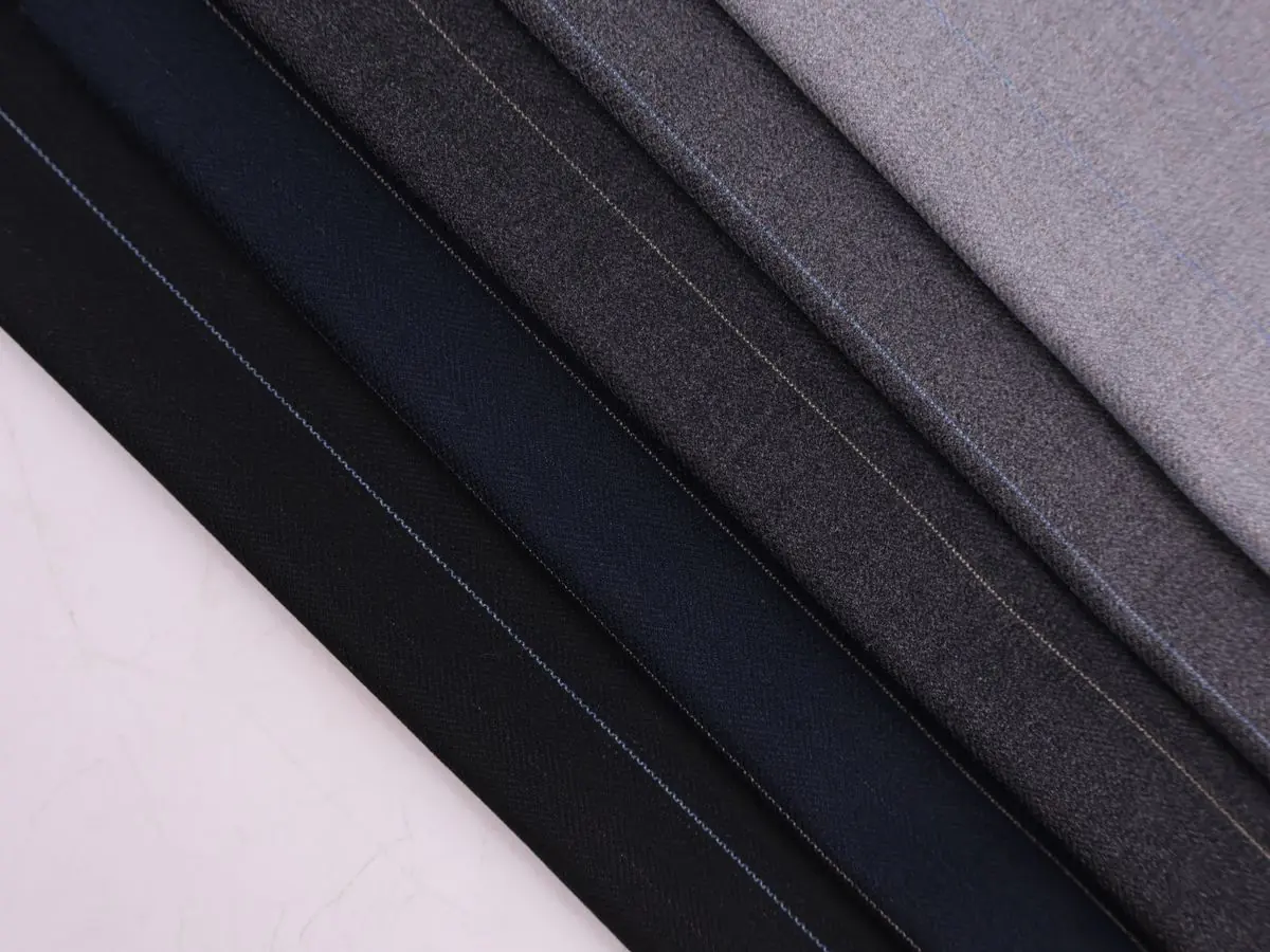 Folded suiting fabrics in navy, charcoal, and grey